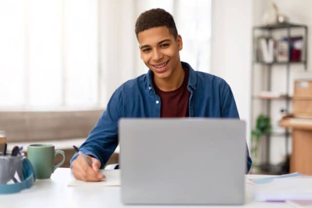 Jeune homme qui est heureux d'écrire sa lettre de motivation pour être animateur