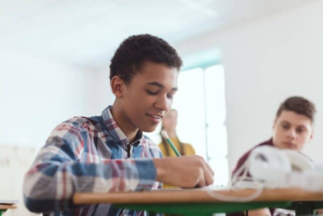 Un collégien heureux de rédiger sa lettre de motivation pour son stage de 3ème